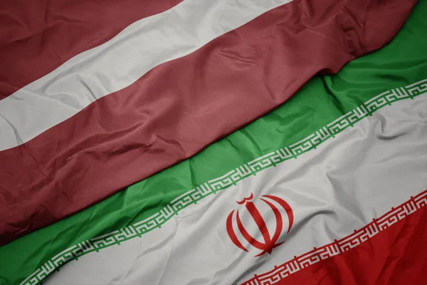 挥舞着五颜六色的伊朗国旗和拉脱维亚国旗. — 图库照片