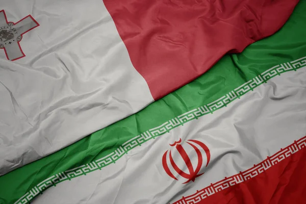 Zwaaiende kleurrijke vlag van Iran en de nationale vlag van Malta. — Stockfoto