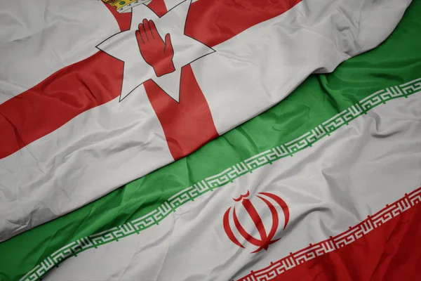 Размахивая красочным флагом Ирана и национальным флагом северной Ирландии . — стоковое фото