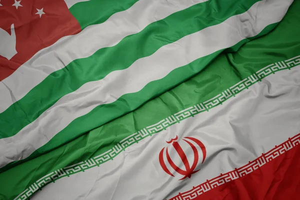 Agitant drapeau coloré de l'iran et drapeau national de l'abkhazie . — Photo