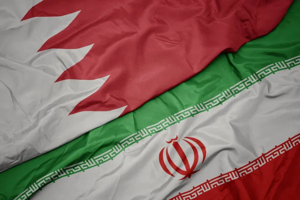 waving colorful flag of iran and national flag of bahrain.