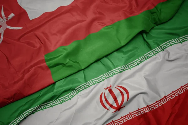 Waving colorful flag of iran and national flag of oman. — Stock Photo, Image