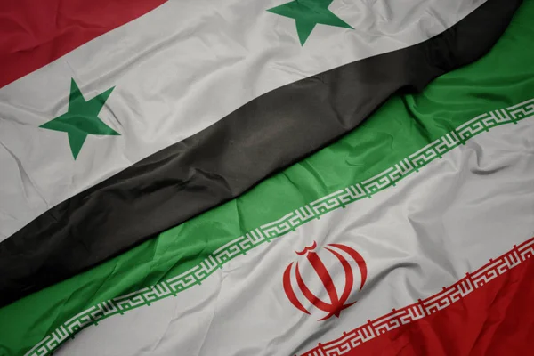 Agitant drapeau coloré de l'iran et drapeau national de la syrie . — Photo