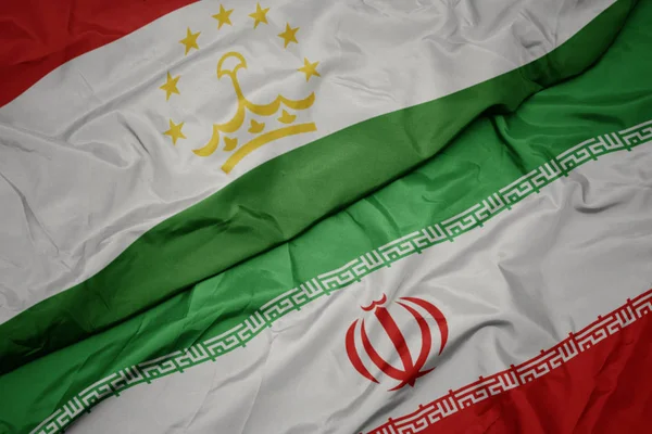 Waving colorful flag of iran and national flag of tajikistan. — Stock Photo, Image