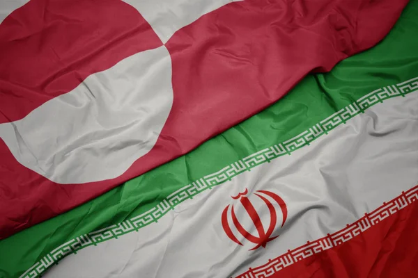 Waving colorful flag of iran and national flag of greenland. — Stock Photo, Image