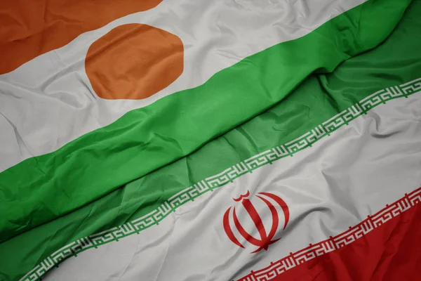 Agitant drapeau coloré de l'iran et drapeau national du niger . — Photo