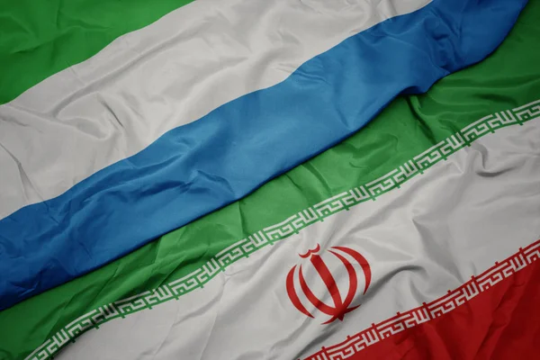 Размахивая красочным флагом Ирана и национальным флагом Сьерра-Леоне . — стоковое фото