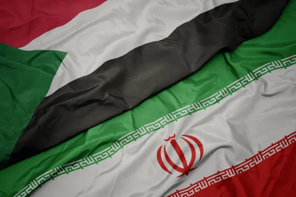 Sventolando bandiera colorata di iran e bandiera nazionale di sudan . — Foto Stock