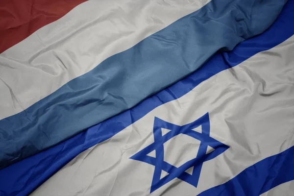 Agitant le drapeau coloré d'Israël et le drapeau national du Luxembourg . — Photo