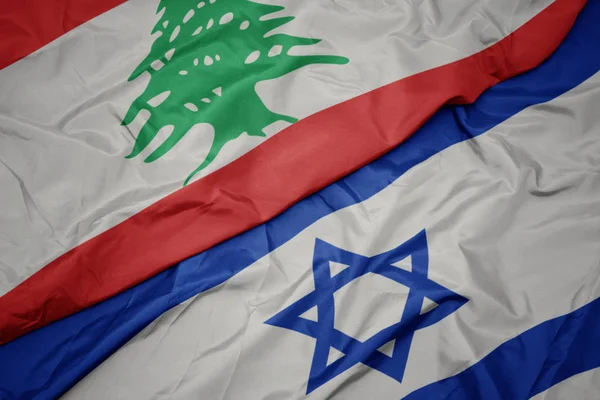 waving colorful flag of israel and national flag of lebanon.