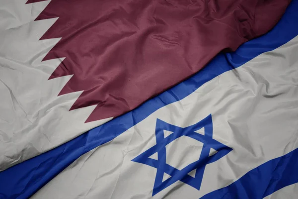 Acenando bandeira colorida de israel e bandeira nacional do qatar . — Fotografia de Stock