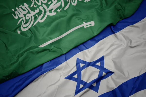 Zwaaiende kleurrijke vlag van Israël en de nationale vlag van Saoedi-Arabië. — Stockfoto