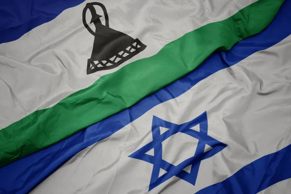 Ondeando colorida bandera de Israel y bandera nacional de Lesotho . —  Fotos de Stock