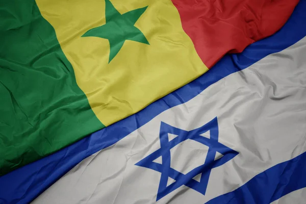 waving colorful flag of israel and national flag of senegal.