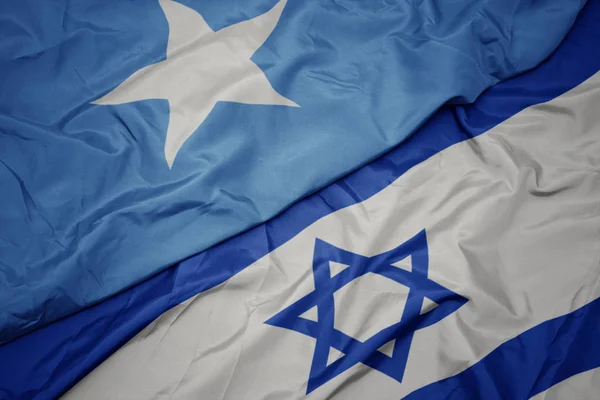 Agitant le drapeau coloré d'Israël et le drapeau national de la somalie . — Photo