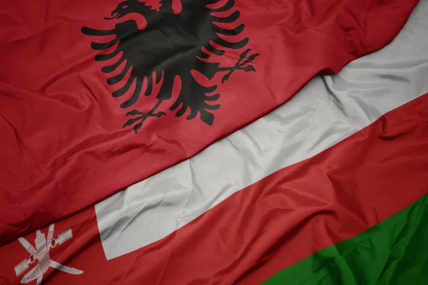 Umman renkli bayrak ve arnavutluk ulusal bayrağı sallayarak. — Stok fotoğraf