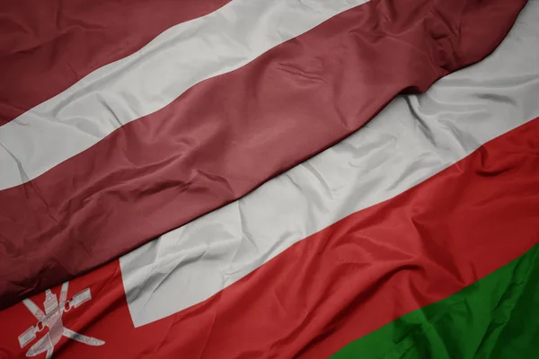 オマーンのカラフルな旗とラトビアの国旗を振る. — ストック写真