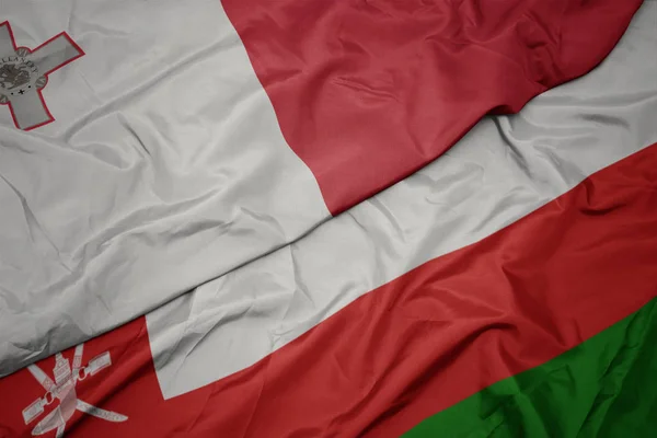 Zwaaiende kleurrijke vlag van Oman en de nationale vlag van Malta. — Stockfoto