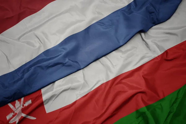 Sventolando bandiera colorata di oman e bandiera nazionale dei Paesi Bassi . — Foto Stock