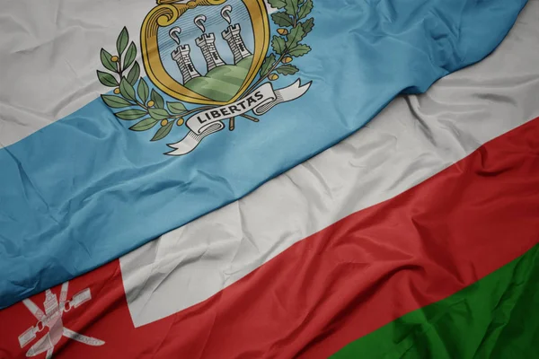 Sventolando bandiera colorata di oman e bandiera nazionale di san marino . — Foto Stock