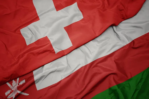 Waving colorful flag of oman and national flag of switzerland. — Stock Photo, Image