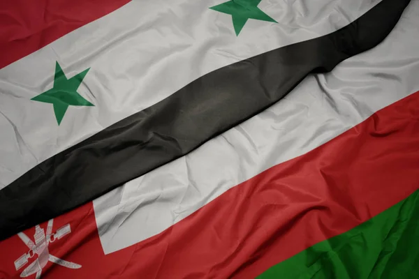 Agitant drapeau coloré d'oman et drapeau national de la syrie . — Photo