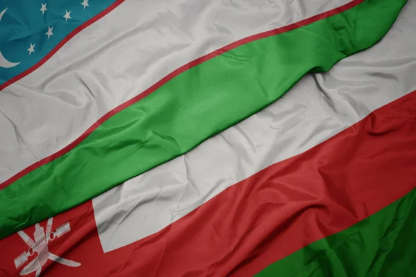 Omán zászlója és Üzbegisztán nemzeti zászlaja hullámzó. — Stock Fotó