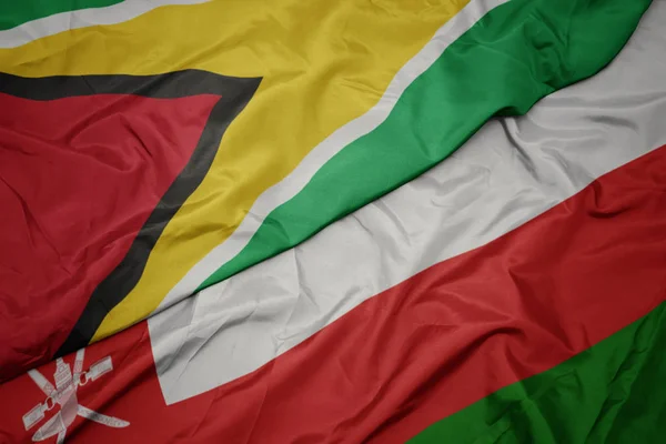 Agitant drapeau coloré d'oman et drapeau national de Guyane . — Photo