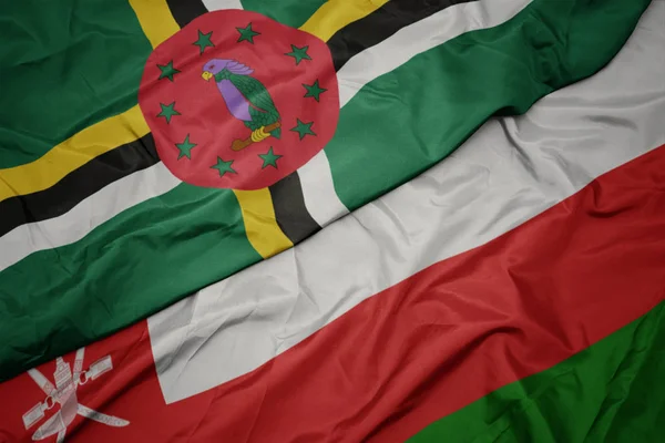 Agitant drapeau coloré d'oman et drapeau national de la Dominique . — Photo