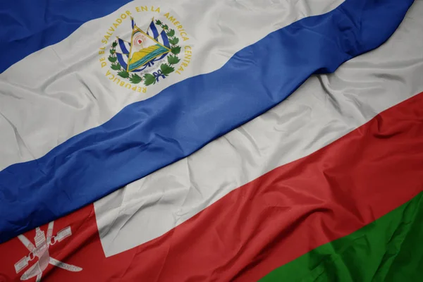 Размахивая разноцветным флагом оманского и национального флага Сальвадора . — стоковое фото