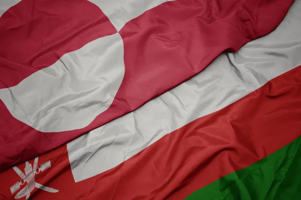 Waving colorful flag of oman and national flag of greenland. — Stock Photo, Image