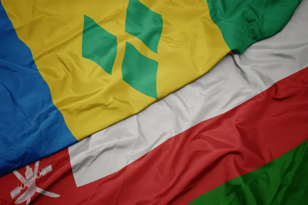 Falujące kolorowe flagi Omanu i flagi narodowej Saint Vincent i Grenadyny. — Zdjęcie stockowe