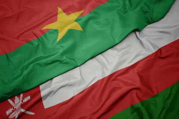 Ondeando colorida bandera de Oman y bandera nacional de Burkina faso . — Foto de Stock