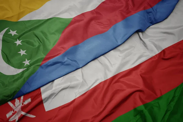 Ondeando colorida bandera de Omán y bandera nacional de las comoras . — Foto de Stock
