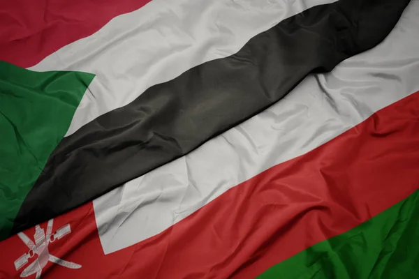 Waving colorful flag of oman and national flag of sudan. — Stock Photo, Image