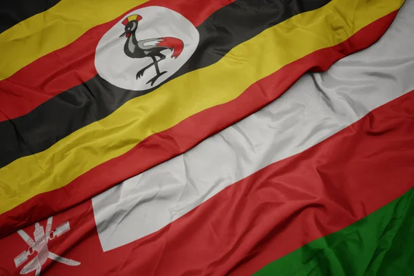 オマーンのカラフルな旗とウガンダの国旗を振る. — ストック写真