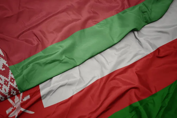 Sventolando bandiera colorata di oman e bandiera nazionale di bielorussia . — Foto Stock
