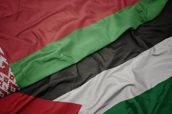 waving colorful flag of palestine and national flag of belarus.
