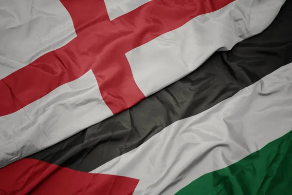 waving colorful flag of palestine and national flag of england.
