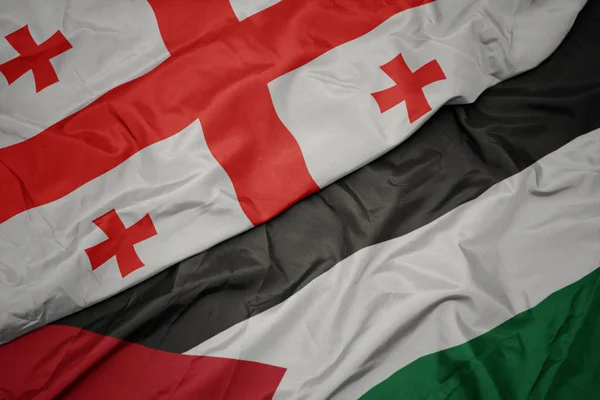 waving colorful flag of palestine and national flag of georgia.