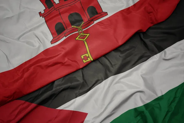 waving colorful flag of palestine and national flag of gibraltar.