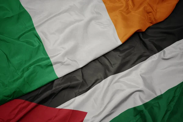 waving colorful flag of palestine and national flag of ireland.