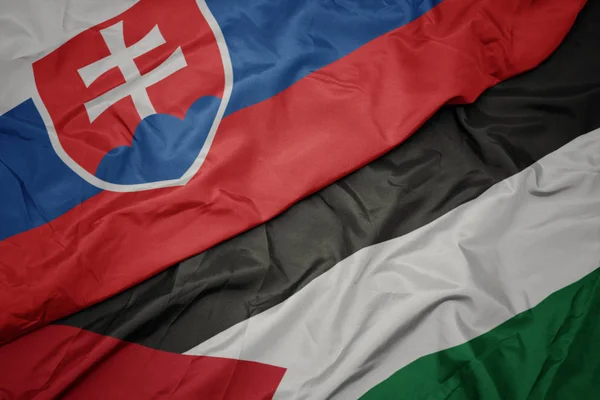 waving colorful flag of palestine and national flag of slovakia.