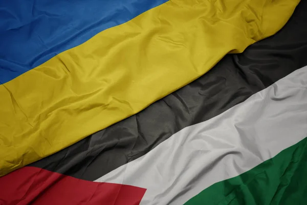waving colorful flag of palestine and national flag of ukraine.