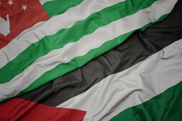 waving colorful flag of palestine and national flag of abkhazia.
