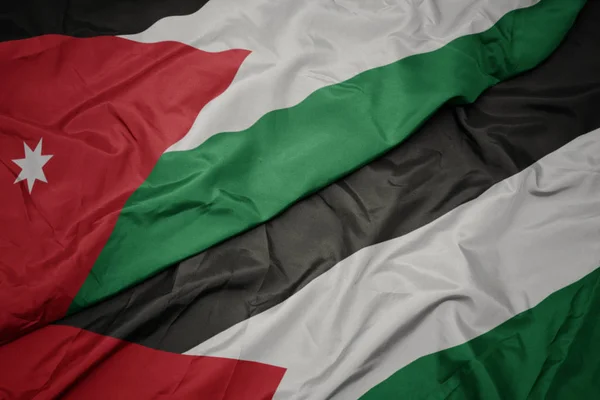 waving colorful flag of palestine and national flag of jordan.