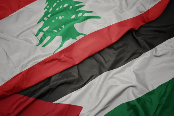 waving colorful flag of palestine and national flag of lebanon.