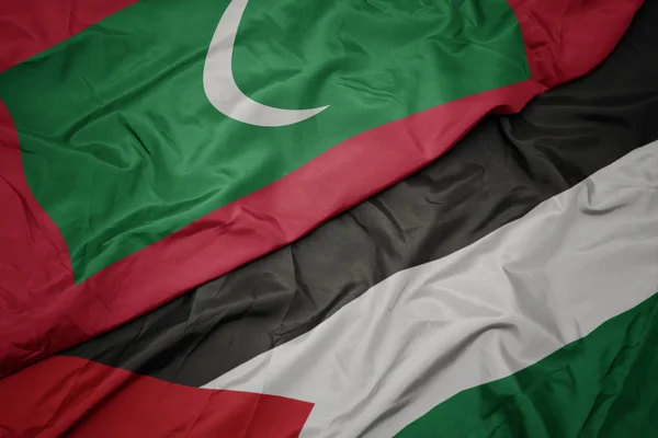 waving colorful flag of palestine and national flag of maldives.