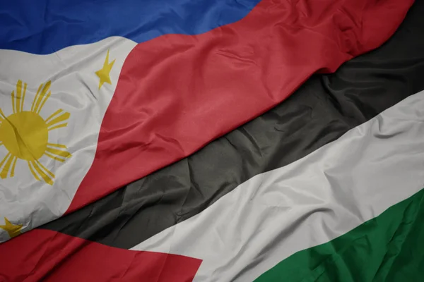 waving colorful flag of palestine and national flag of philippines.