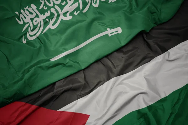 waving colorful flag of palestine and national flag of saudi arabia.